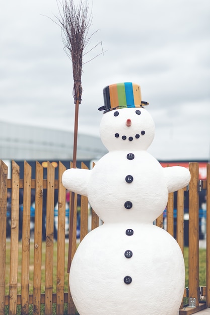 Photo snowman with a pot and broomstick cloudy day