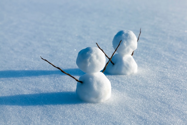 Snowmen made of snow in winter, small snowmen stand on the snow in winter