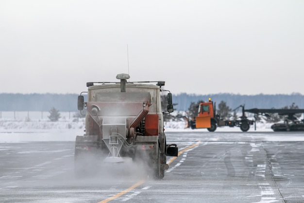 写真 雪掃除機が雪嵐で空港のタクシーウェイを掃除する