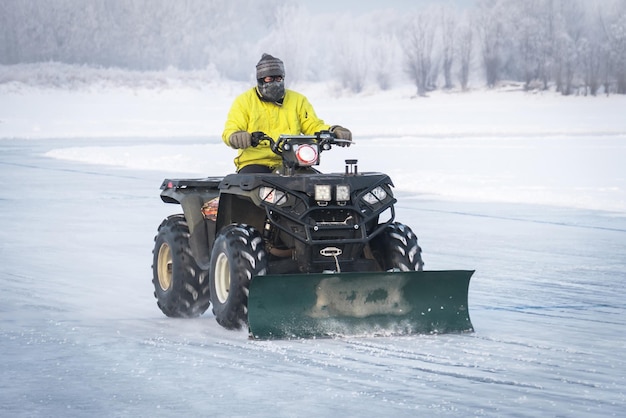 snowplow removing snow on the street after blizzard ATV converted into a plow truck Clearing the ice of snow cleaning of the rink on the street snow removal machine A very cold frosty weather