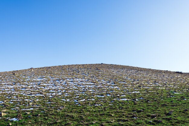 Foto collina alpina innevata con erba rada