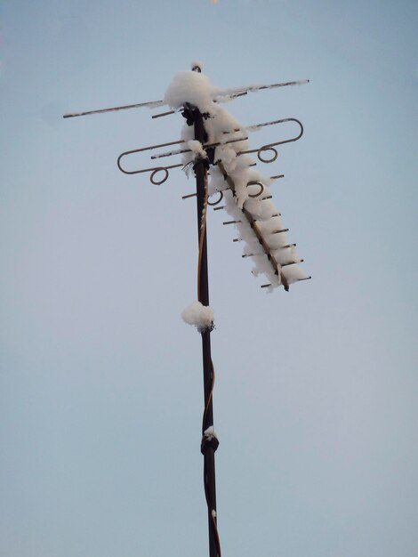 写真 青い空を背景に屋根の上の雪に覆われたアンテナ