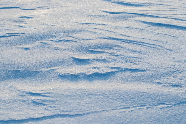 雪に覆われた背景、明確な雪の層を伴う日光の下での朝の吹雪の後の雪に覆われた地球の表面