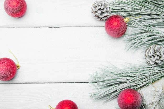 Snowy branch christmas tree and cone and red ball on white wooden vintage surface