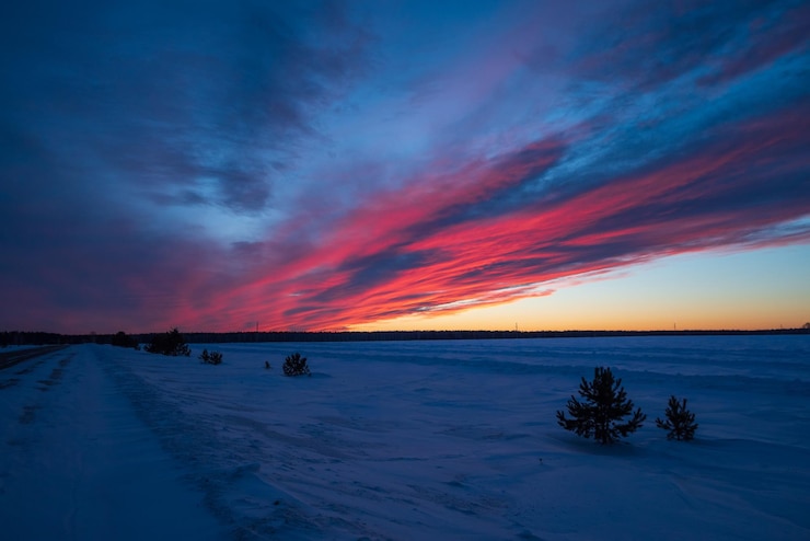 Photo snowy field with a sunset creating a red sky afterglow in the natural landscape