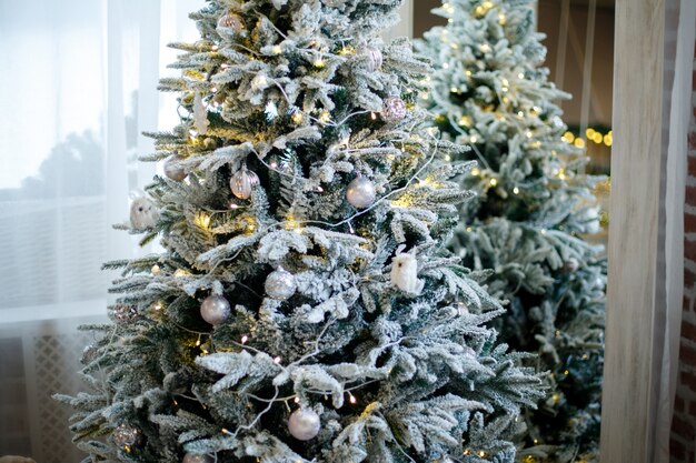 Snowy fluffy Christmas tree decorated with white toys and garlands