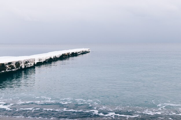 Snowy and frozen pier and a calm sea