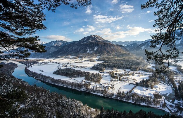 Photo a snowy landscape with a river and mountains in the background