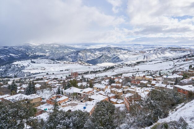 Foto un paesaggio innevato con un villaggio in primo piano e neve al suolo.