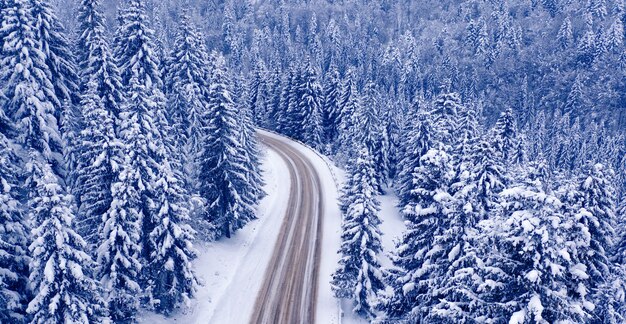 雪に覆われた山道と森、ドローンビュー。雪に覆われた山道と森、ドローンビュー。素晴らしい冬の風景。