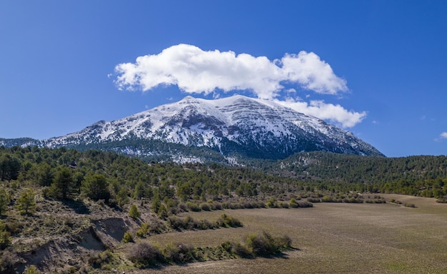 Snowy mountain with clouds over its top. Winter landscape. First snow of the year. La Sagra. Granada