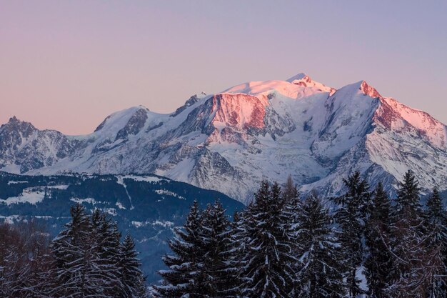 A snowy mountain with a pink light on the top