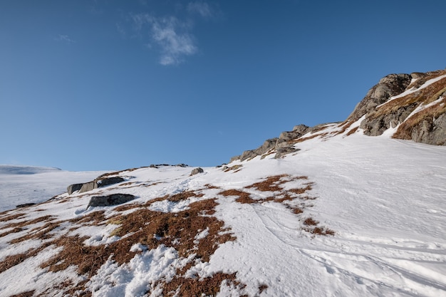 Snowy mountain with rocks and blue sky in alpine on winter