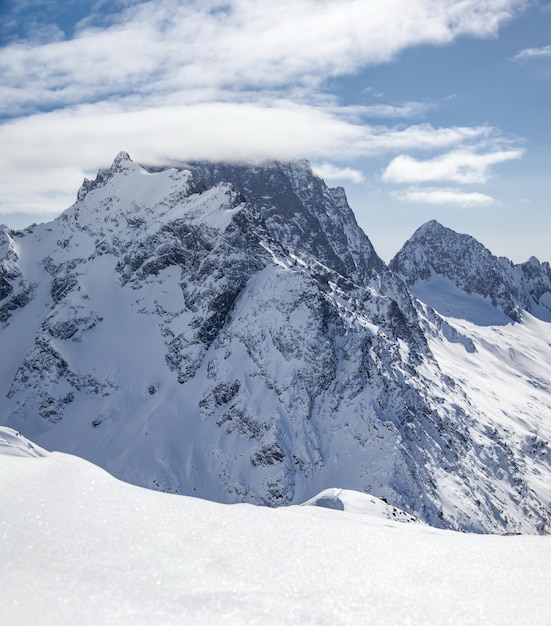 Snowy Mountains peaks in the clouds blue sky Caucasus