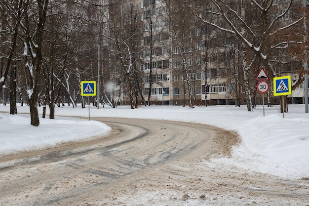 Snowy road and pedestrian crossing with road signs