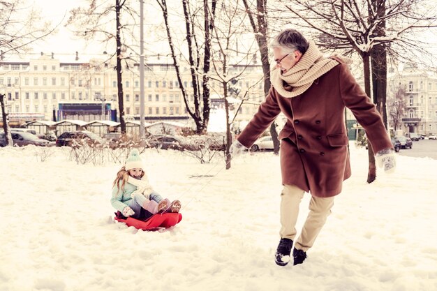 Inverno nevoso. affascinante ragazza bionda seduta sulla slitta e mantenendo il sorriso sul suo viso