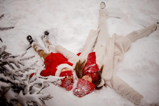 雪の降る冬がやってきて、暖かい服を着た母と息子がクリスマス ツリーの近くで雪の中で楽しんでいます