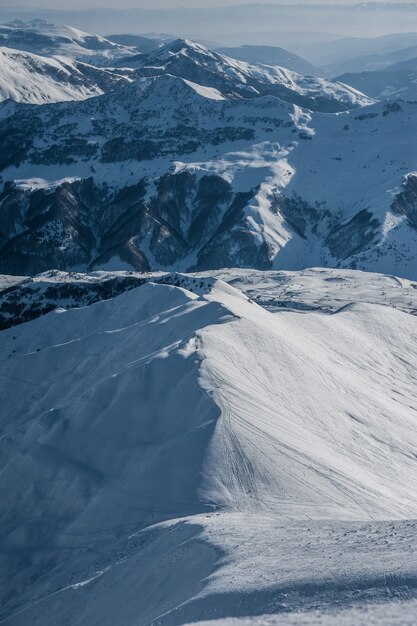 Snowy winter mountains in sun day. Caucasus Mountains, Georgia, from ski resort Gudauri