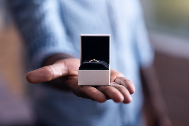 Photo so beautiful. close up of an engagement ring held by young happy african man preparing for making proposal to his girlfriend.