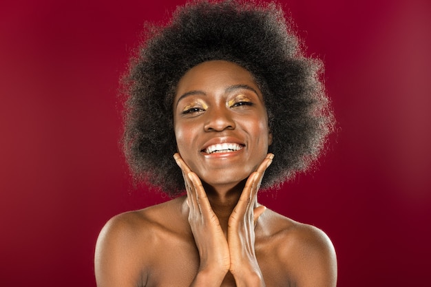 So beautiful. Delighted nice woman smiling while standing against red wall