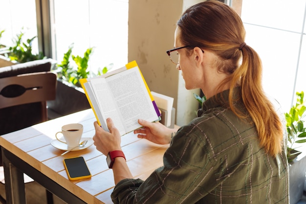 Photo so engaging. good looking smart man looking at the book pages while being engaged in the activity