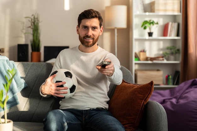 So exciting. young interested guy sitting on sofa and\
expressing exhilaration while watching sport game with excited\
emotions