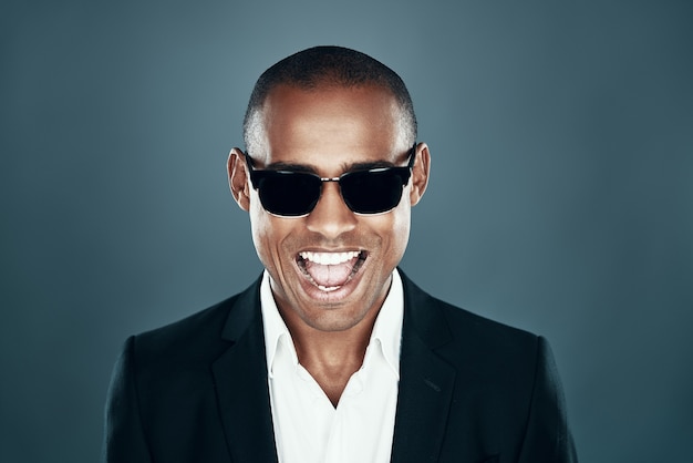 So handsome! charming young african man in full suit looking at
camera and smiling while standing against grey background