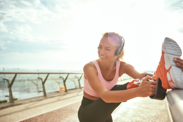 写真 義足を伸ばして聞いているヘッドフォンで陽気な障害のある女性のとても幸せなクローズアップ