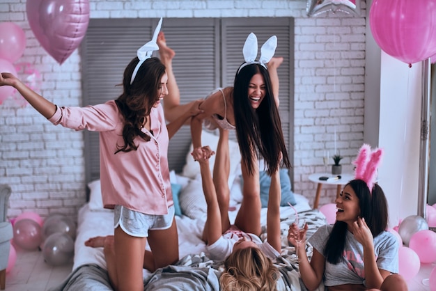 너무 행복한! 토끼 귀에 장난을 치는 젊은 여성들은 홈 파티를 즐기면서 재미있고 웃고 있습니다.