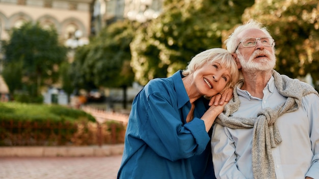 So happy together portrait of beautiful senior woman leaning at shoulder of her husband and smiling