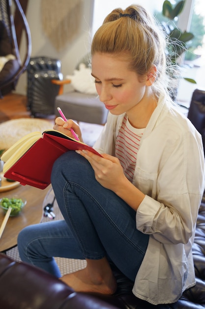 Photo so shy. cute woman sitting on leather sofa while making plans for the day