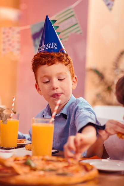 So tasty. Attentive kid pressing lips while looking downwards