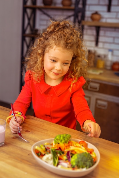 Così gustoso. bambino contento che continua a sorridere mentre va a mangiare cibo sano