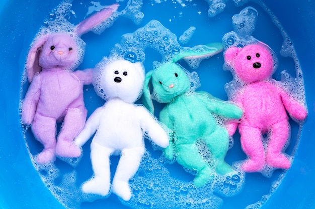 Soak rabbit doll with  toy teddy bear in laundry detergent water dissolution before washing.  Laundry concept,