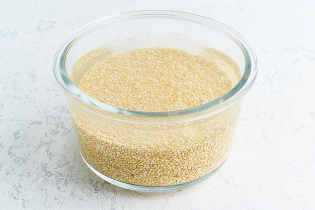Soaking quinoa cereal in water to ferment cereals and neutralize phytic acid. Large glass bowl