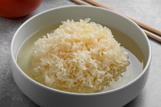 Soaking a whole dried white fungus in water in a bowl close up