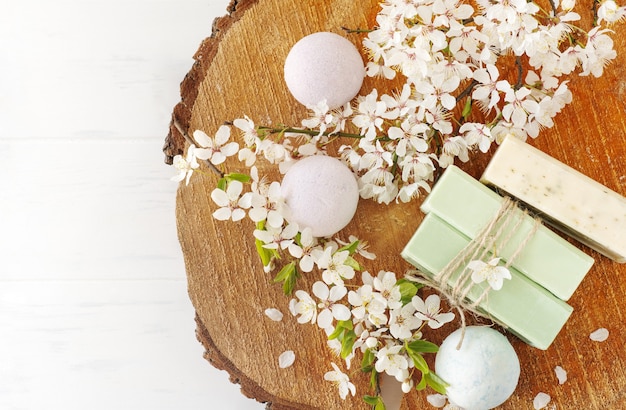 Bandiera di sapone. sapone naturale aromatico e bomba da bagno con fiori di sakura su fondo in legno, vista dall'alto