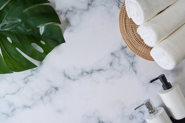 Soap bottles and white towels on marble background.