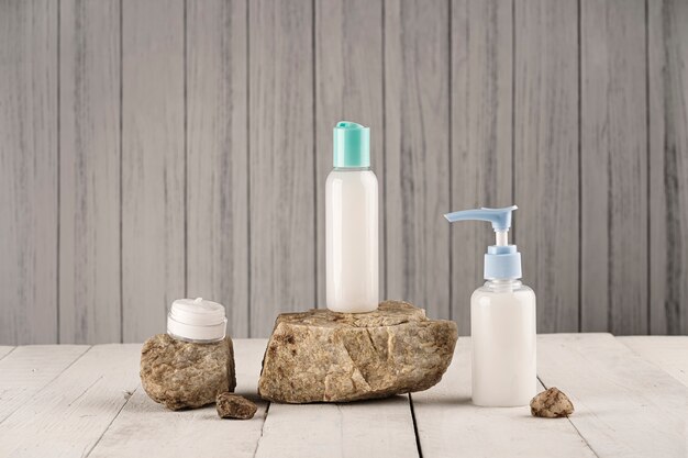 Soap and cream containers on natural stones and wooden table