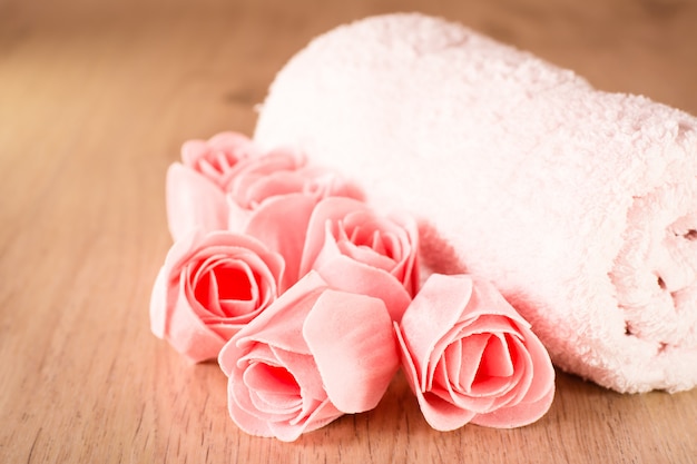 Soap in the form of roses and a towel on a wooden background