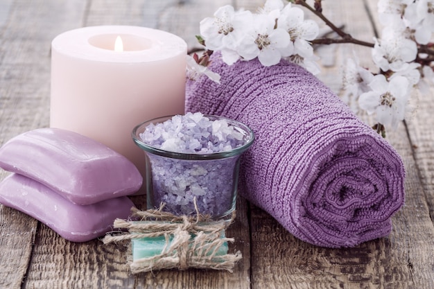 Soap, sea salt in glass bowl with towel for bathroom procedures and burning candle with flowering branch of apricot tree