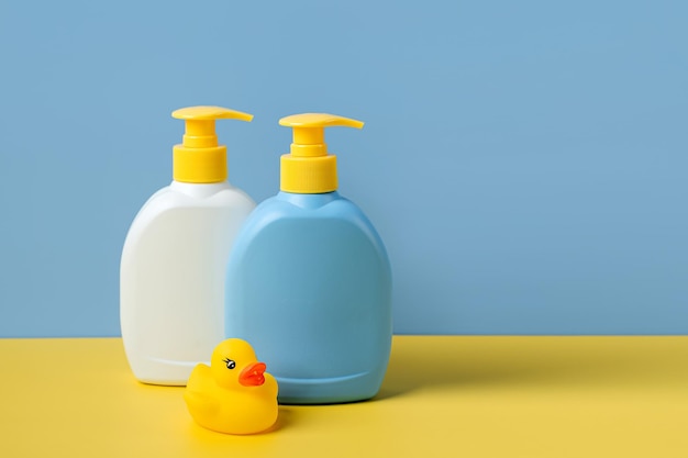 Soap or shampoo bottles with cute duck on blue background. Baby bathing accessories