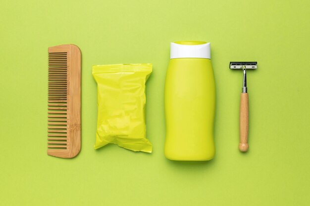 Soap shampoo comb and razor on a green background