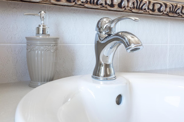 Soap and shampoo dispensers on Water tap sink with faucet in expensive loft bathroom