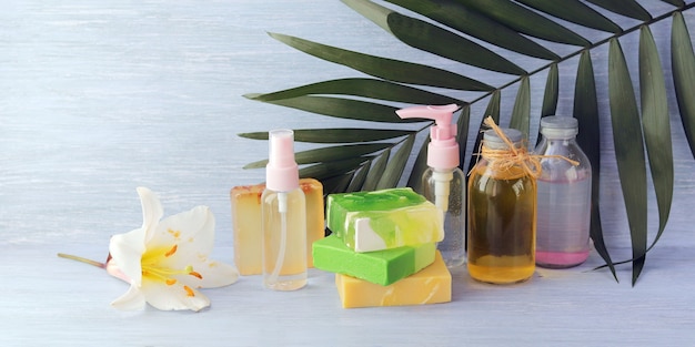 石鹸、スプレー、ユリの花、木製のテーブルにアロマオイルを入れたガラス瓶、スパ、自然化粧品
