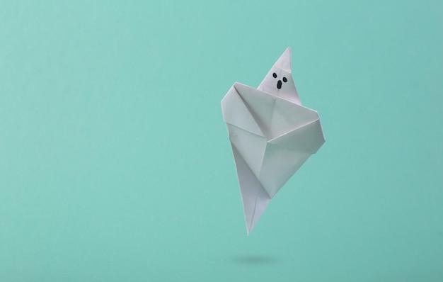 Fantasma di origami in ascesa su sfondo blu concetto creativo di halloween