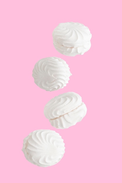 Soaring white zephyr marshmallow on pink background sweet food levitation