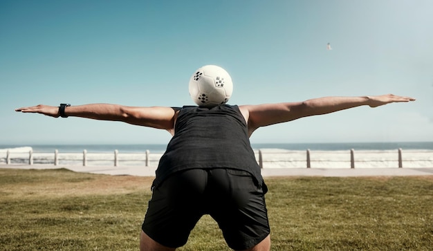 Футбольный мяч балансирует назад и спортивная тренировка спортсмена-мужчины на пляже для тренировки. Упражнения для фитнеса и кардио для здоровья человека на поле у морской воды, океана и природы летом.
