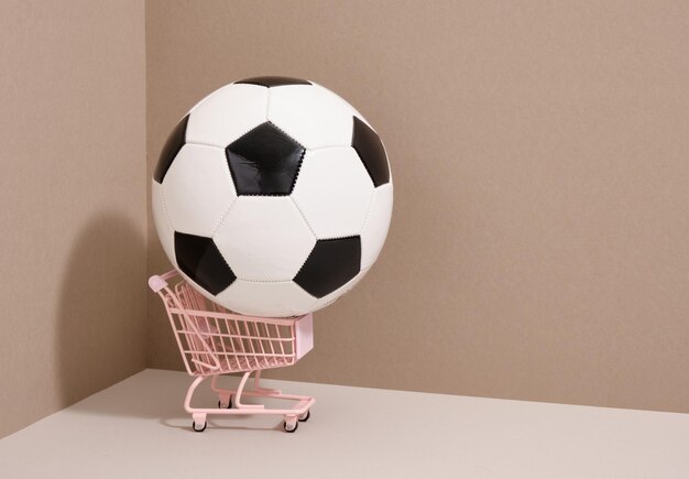 A soccer ball lies in a pink metal shopping cart Copy space for text