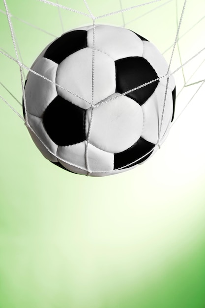 Soccer ball in the net on green background